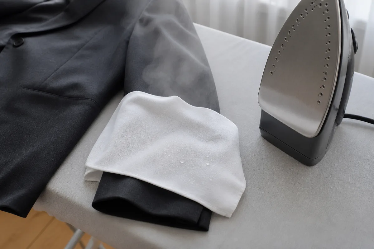 Pattemouille en coton uni posée sur une manche de veste sur la table à repasser